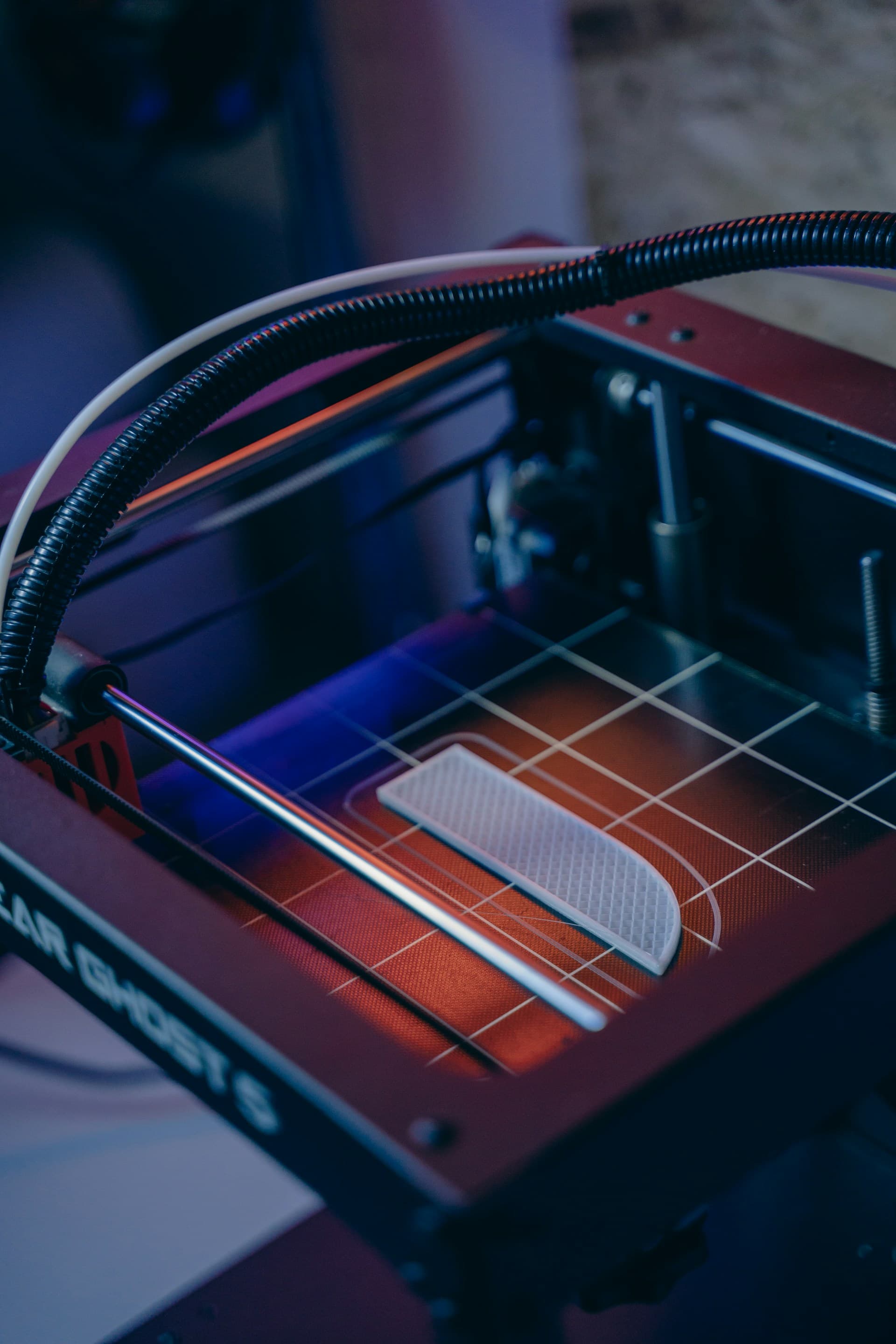 FDM 3D printer mid-print with a white part on the heated bed