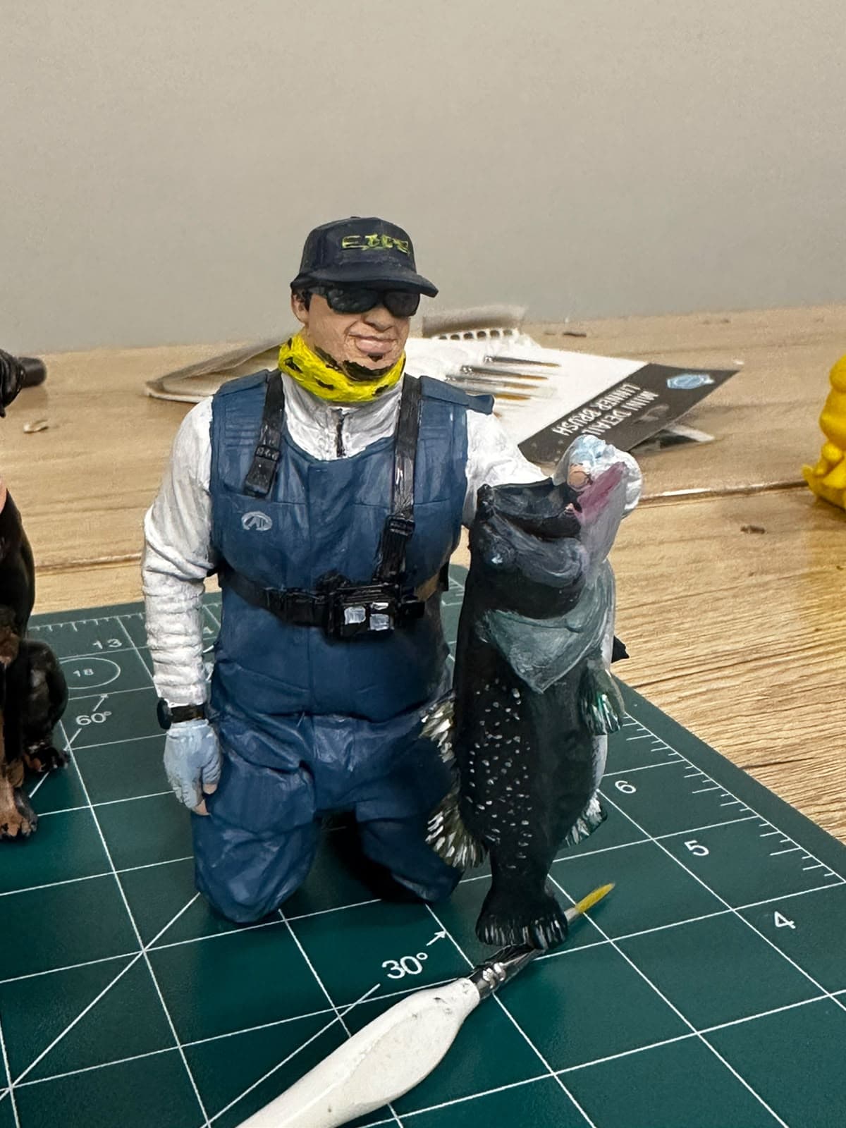 Custom hand-painted figurine of a fisherman holding his catch, side angle