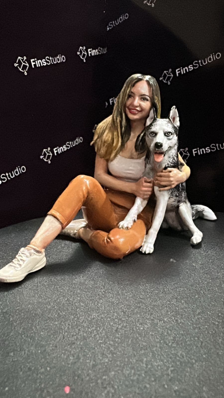 Custom painted figurine of a woman sitting with her husky, Fins Studio backdrop