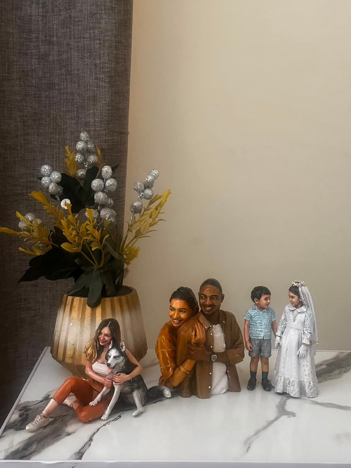A lineup of finished custom figurines, including a pet portrait, a couple, and two children
